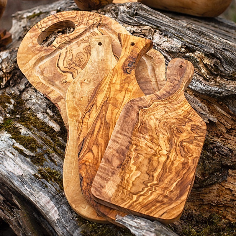 Three wooden cutting boards on top of a log.