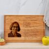 A wooden recipe cutting board with engraved recipe and a picture of a woman.