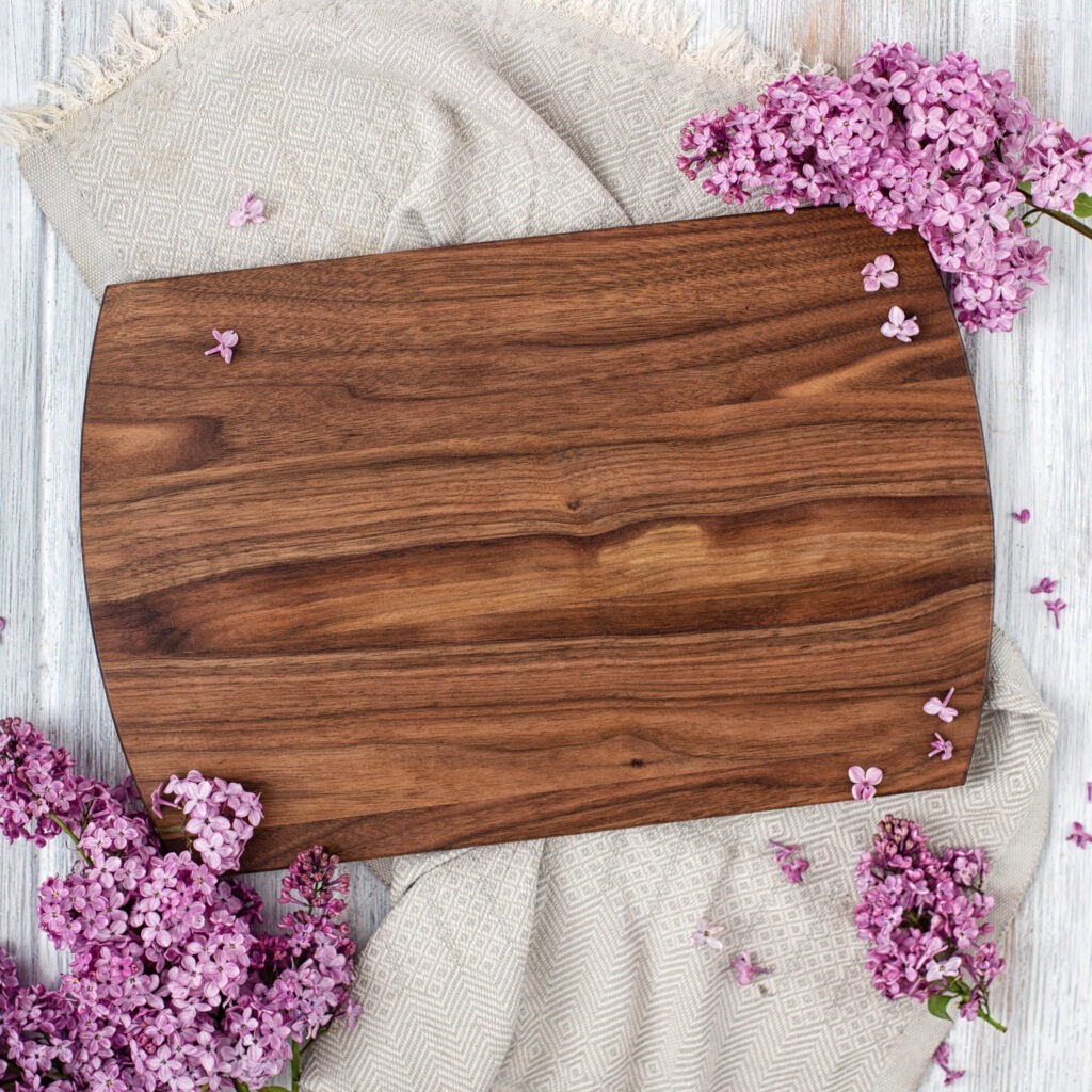 A wooden cutting board with purple flowers on it.