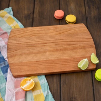 A wooden cutting board with lemons and limes on it.